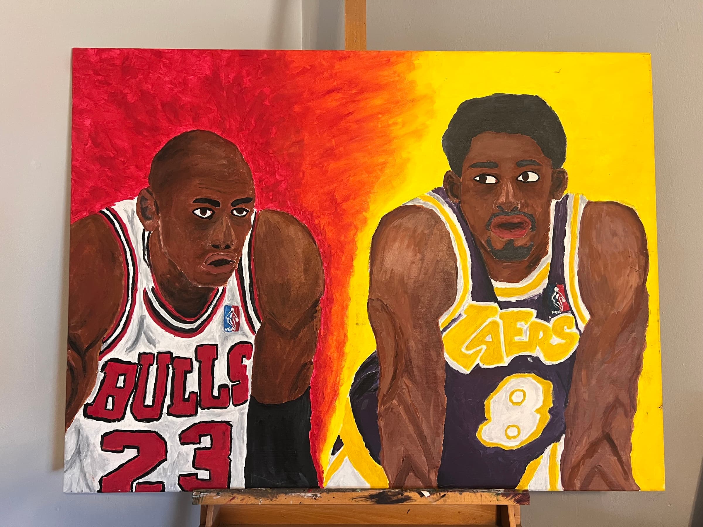 A painting on an easel of two basketball players in red and yellow-purple uniforms, numbers 23 and 8